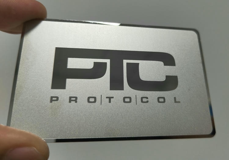 ภาพที่ 3: ภาพระยะใกล้ของบัตรโลหะหรูสำหรับภาพลักษณ์แบรนด์พรีเมียม PTC โดยเน้นสีเงิน โลหะ และรายละเอียดโลโก้หรือข้อความแบบพิเศษ สำหรับการมีส่วนร่วมของลูกค้าและการจัดการชื่อเสียงธุรกิจ.