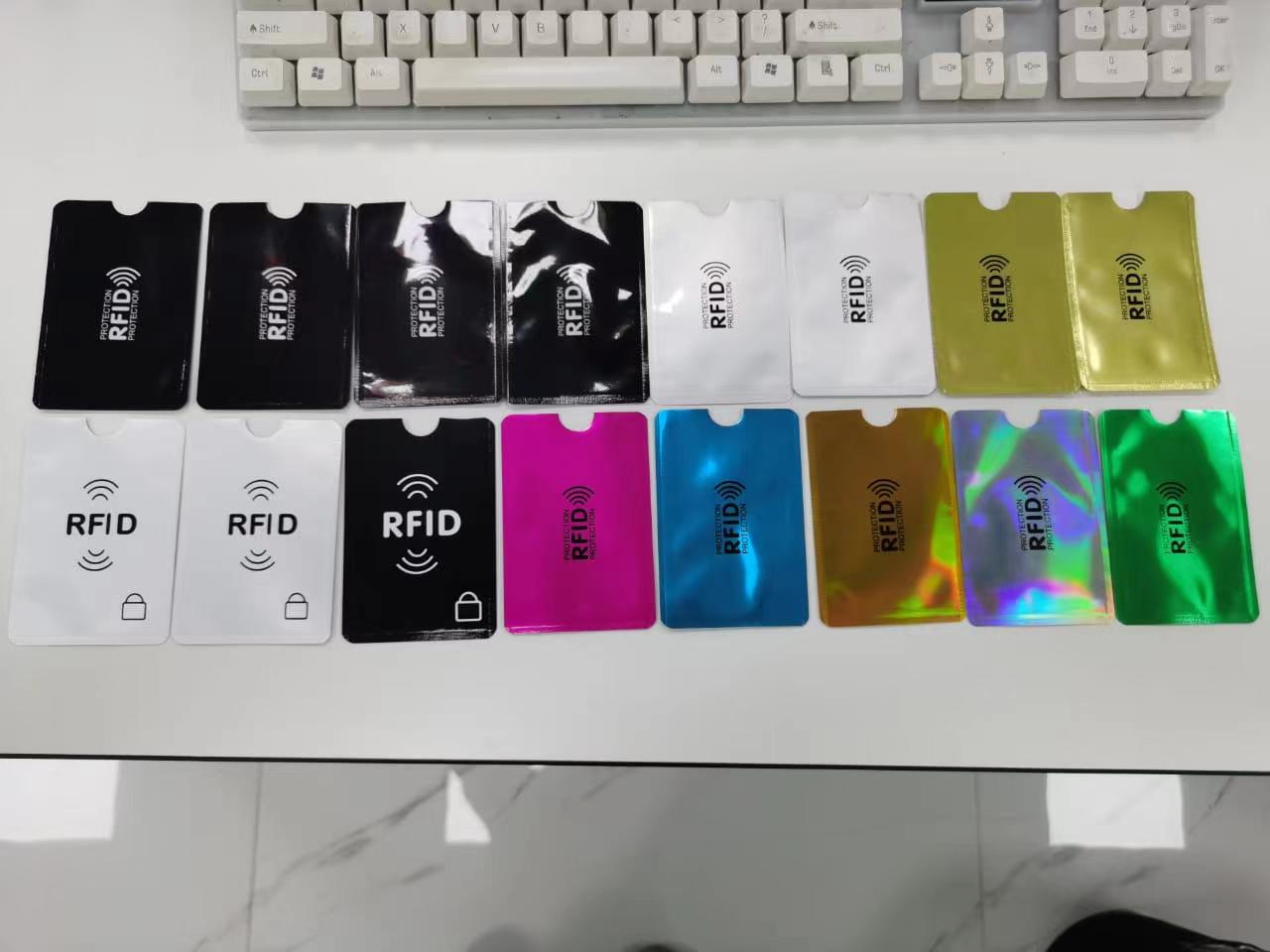ซองกันสัญญาณ RFID หลากหลายแบบจัดเรียงเป็นแถวใต้คีย์บอร์ดเพื่อเปรียบเทียบผิวเงา ผิวด้าน และผิวเมทัลลิก