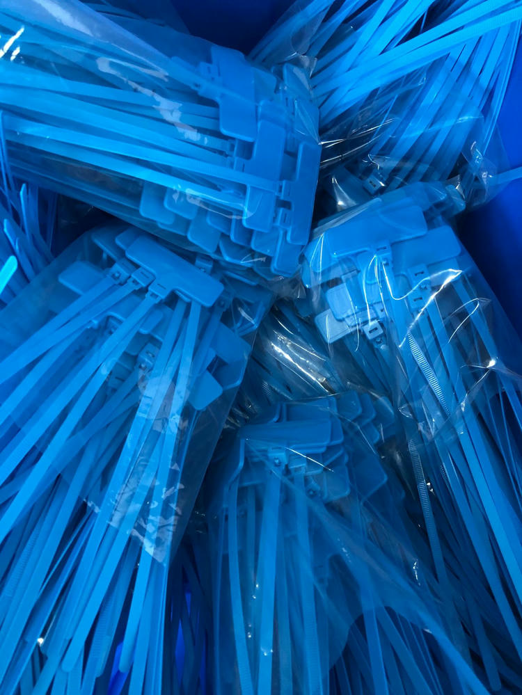 RFID zip tie แท็ก รุ่น Z31079-1 สีน้ำเงินที่บรรจุแล้วถูกมัดรวมในถุงใส แสดงความพร้อมสำหรับการจัดส่งแบบจำนวนมากและการจัดเรียงสายรัดที่สม่ำเสมอ