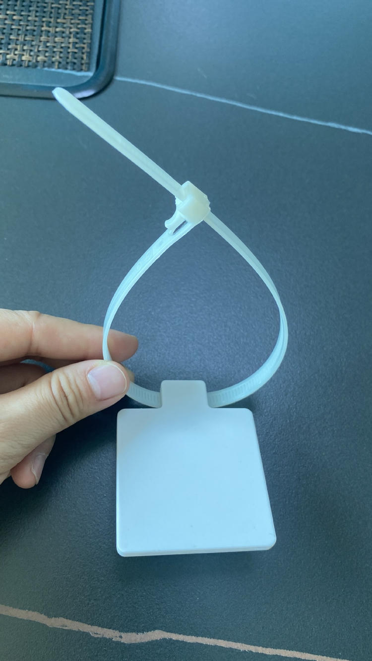 ภาพระยะใกล้แสดง RFID zip tie แท็ก รุ่น Z5555-1 โดยหัวล็อกเข้าที่และปลายสายรัดยื่นขึ้นเหนือแผงสี่เหลี่ยม