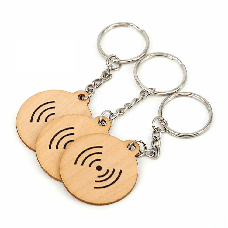 ภาพที่ 6: ภาพนี้แสดงพวงกุญแจ RFID ไม้จิ๋วสองความถี่สำหรับเข้าออกและจ่ายเงิน โดยเน้นไม้ธรรมชาติ โครงสร้างเสาอากาศและชิปภายใน และการเชื่อมต่อแบบไร้สัมผัสหรือไร้สาย.
