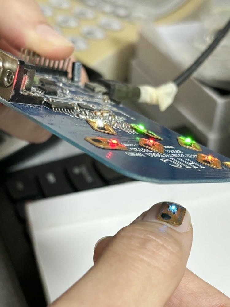 6) ภาพนี้แสดงแท็กเสียง RFID พร้อม NFC LED สำหรับจอแสดงผลและอีเวนต์ FLED1006-1 โดยเน้นสีน้ำเงิน ไฟแสดงสถานะ LED และสีและรายละเอียดที่มองเห็นชัด.