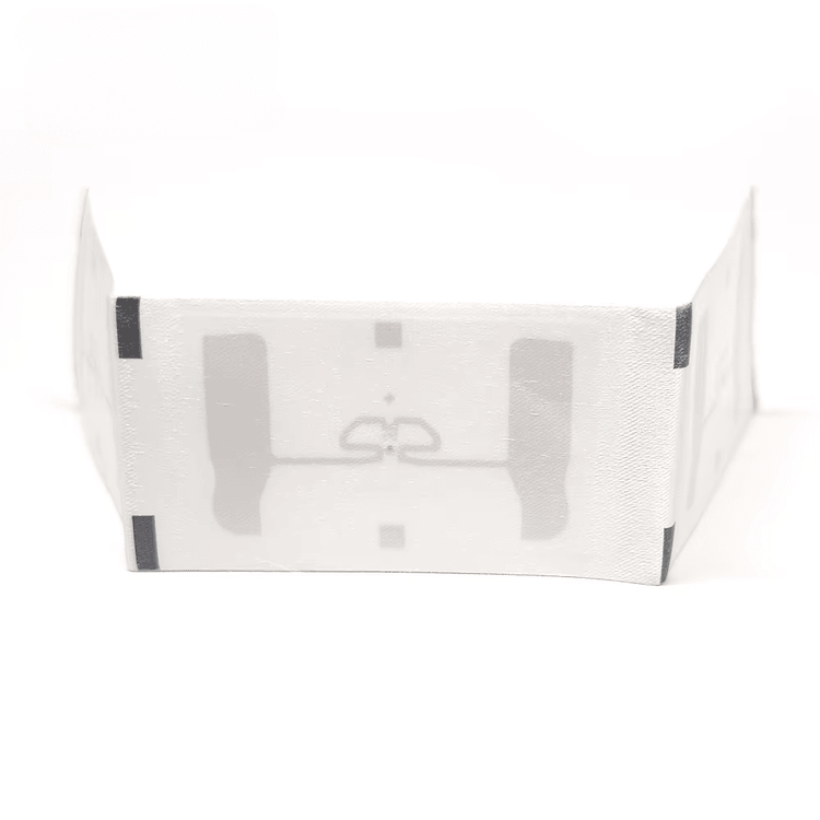 3) มุมมองแบบเอียงของแท็กผ้าทอ UHF RFID ซักได้สำหรับติดตามเสื้อผ้า โดยเน้นสีขาว สิ่งทอ และโครงสร้างเสาอากาศและชิปภายใน สำหรับการติดตามผ้าและเสื้อผ้า.