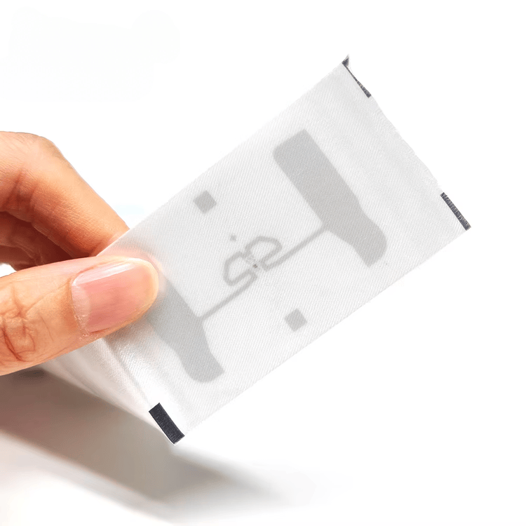 4) ภาพนี้แสดงแท็กผ้าทอ UHF RFID ซักได้สำหรับติดตามเสื้อผ้า โดยเน้นสีขาว สิ่งทอ และโครงสร้างเสาอากาศและชิปภายใน ขณะถือเพื่อแสดงการใช้งานจริง และในลักษณะติดตั้งกับชิ้นงาน สำหรับการติดตามผ้าและเสื้อผ้า.