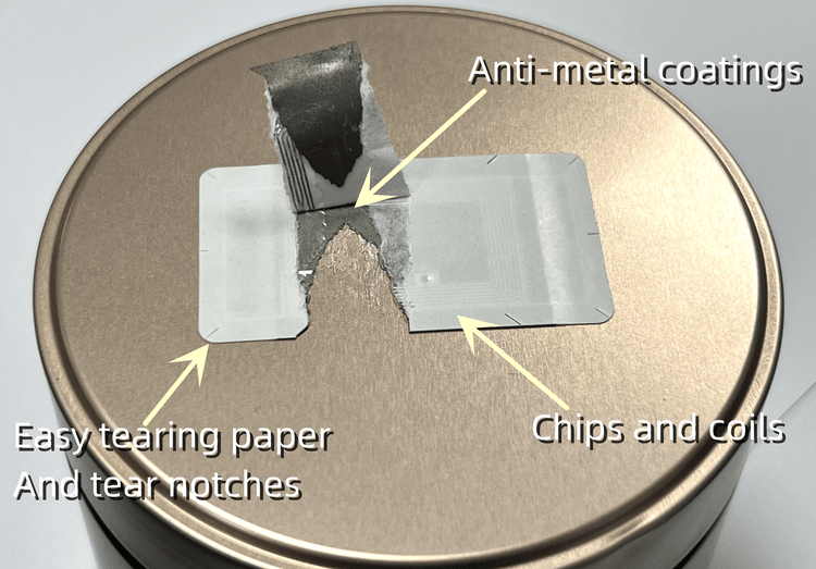 ภาพนี้แสดงฉลาก RFID แบบเปราะบางที่ฉีกขาดบนฝาโลหะ พร้อมคำอธิบายชี้ไปที่ขดลวดชิปและชั้นกระดาษที่ฉีกง่าย