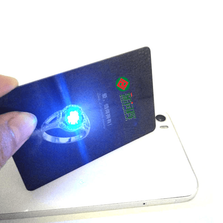 บัตร NFC พร้อมไฟ LED แสดงในภาพแตะแบบใกล้ที่ไฟ LED สีน้ำเงินสว่างขึ้นระหว่างการอ่านด้วยโทรศัพท์เพื่อการยืนยันอย่างรวดเร็ว