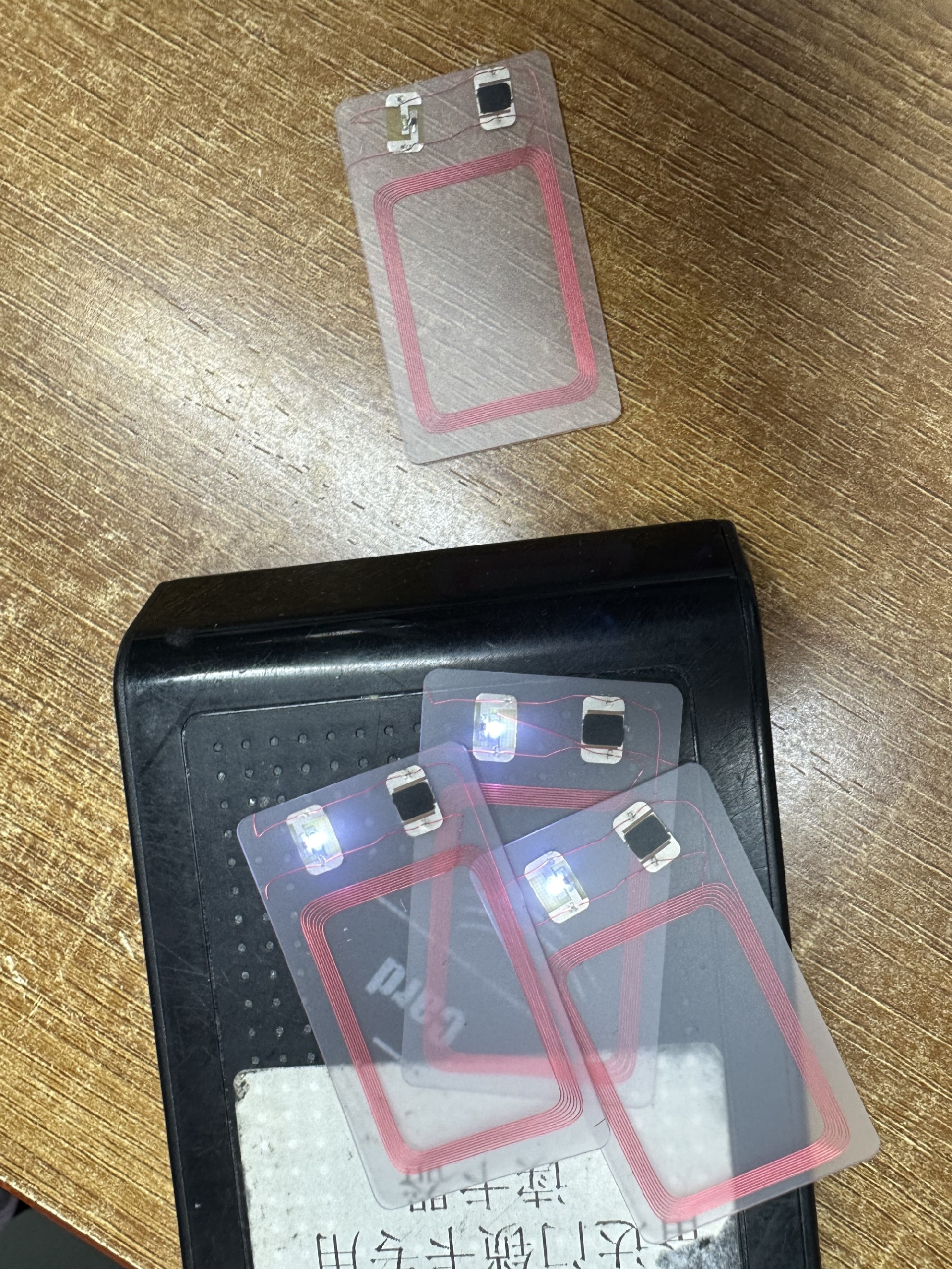 ตัวอย่างบัตร NFC พร้อมไฟ LED บนโต๊ะทำงานข้างเครื่องอ่าน แสดงการยืนยันด้วยไฟ LED ระหว่างการทดสอบแบบไม่สัมผัสซ้ำๆ