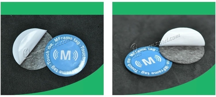 แท็ก RFID กันโลหะ D35mm ถูกแสดงโดยเปิดชั้นกาวด้านหลังสีขาวออกบางส่วน เพื่อให้เห็นโครงสร้างกาวและรูปแบบแท็กวงกลม