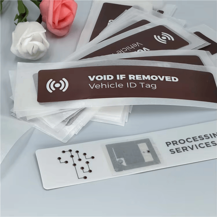 6) ภาพนี้แสดงแท็กกระจกหน้า UHF RFID สำหรับจัดการยานพาหนะ VOID IF REMOVED โดยเน้นโครงสร้างเสาอากาศและชิปภายใน สำหรับงานยานพาหนะ ยางรถ และการจัดการกองรถ และการติดตั้งกลางแจ้งและบนพื้นผิวงานก่อสร้าง.