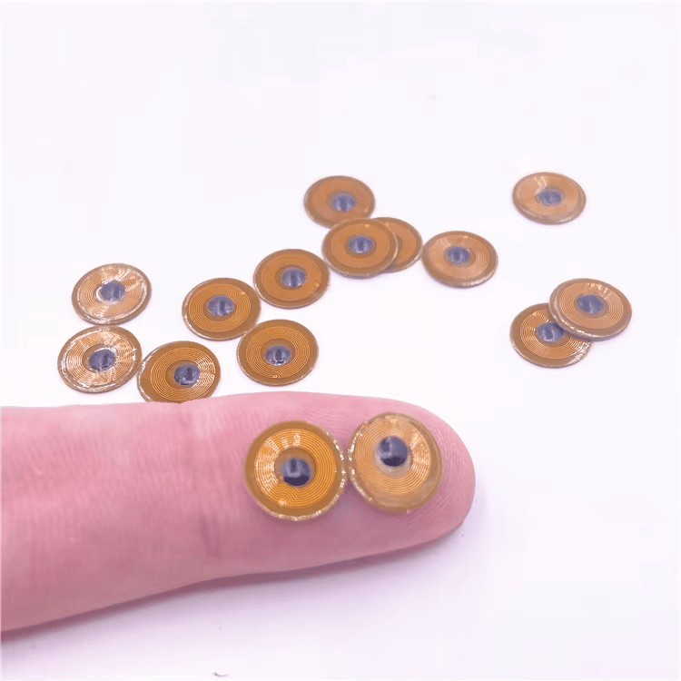 ป้าย RFID ขนาดเล็ก FPC10-1 สองชิ้นบนปลายนิ้วแสดงให้เห็นรูปแบบเล็กพิเศษ 10 มม. สำหรับการติดตามแบบฝังบนโลหะ