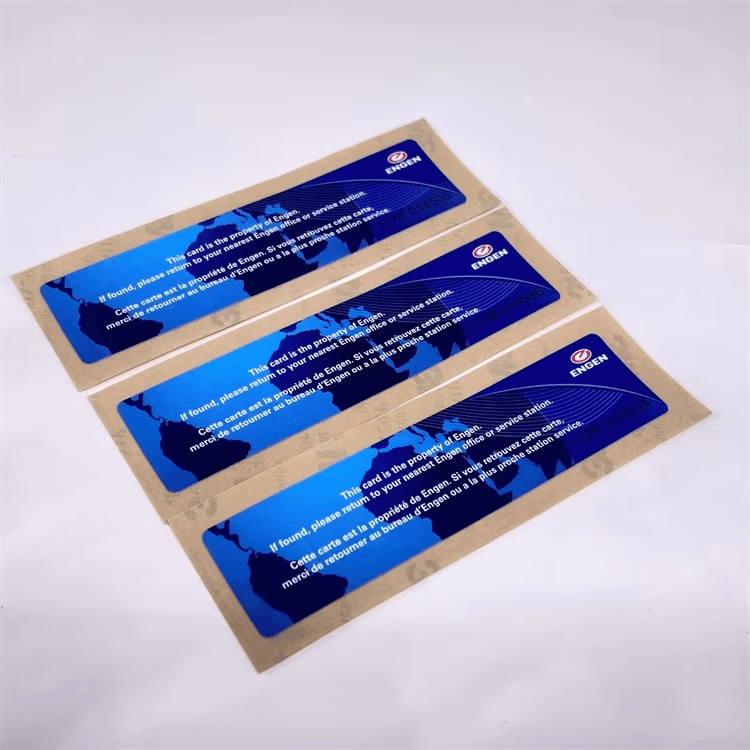 สติกเกอร์ติดกระจกหน้ารถ RFID สีน้ำเงินสามแผ่นในซองคราฟต์ถูกจัดวางเป็นเซ็ตเพื่อแสดงถึงเอกสารยืนยันยานพาหนะที่พร้อมติด
