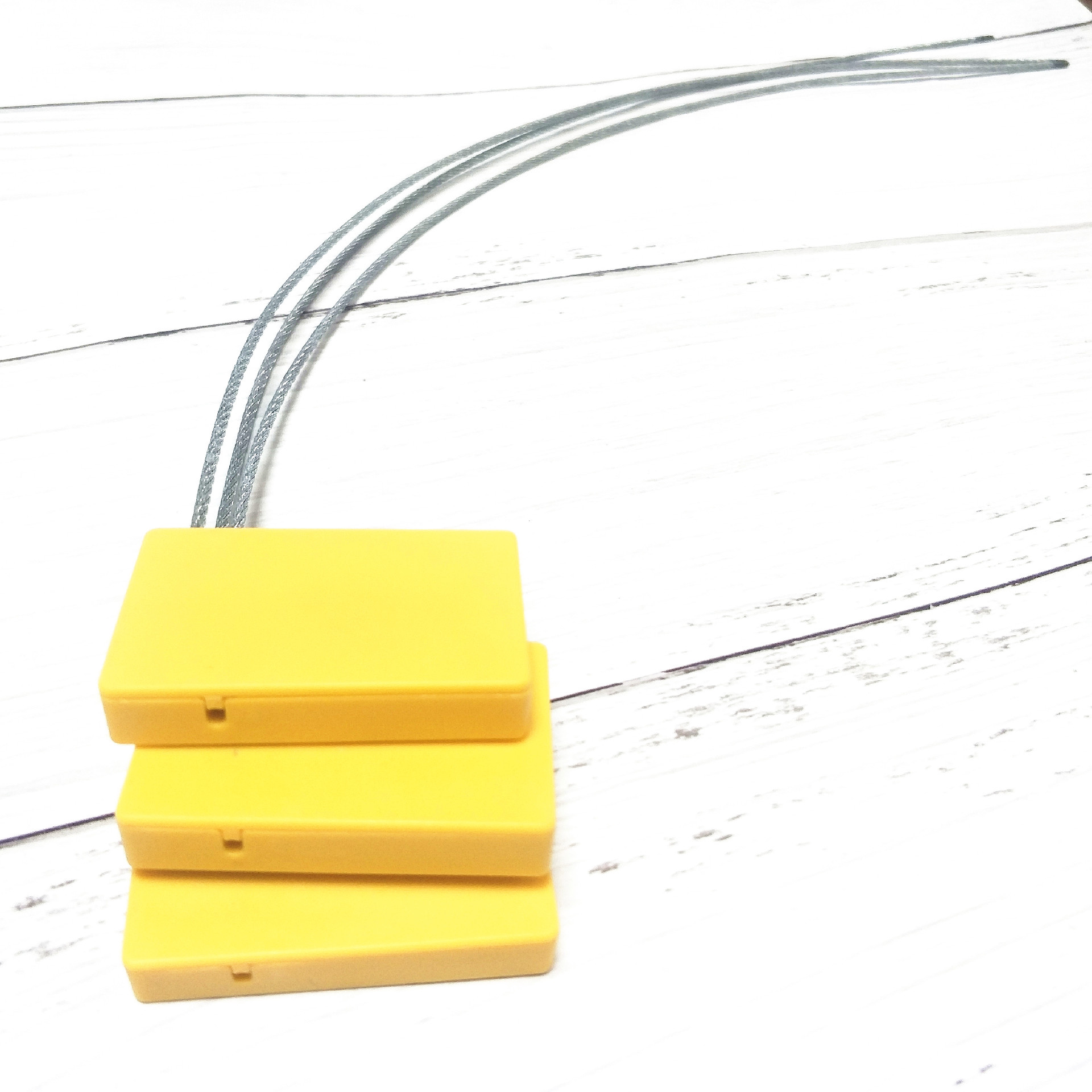 SS4428-1 RFID security seals สีเหลืองสามชิ้นวางซ้อนกันในมุมมองด้านหน้าพร้อมสายเคเบิลเหล็กยาวโค้งขึ้นอย่างราบรื่นเหนือขึ้นไป