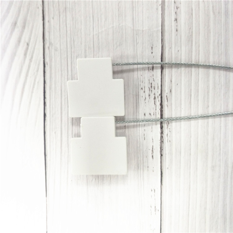 ซีลนิรภัย RFID รุ่น SS4544-1 สีขาวสองชิ้นวางในแนวตั้งโดยมีสายเคเบิลเหล็กทอดยาวบนพื้นหลังลายไม้
