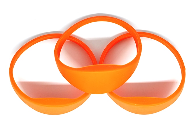 มุมมองด้านหน้าแบบโฟกัสของสายรัดข้อมือ RFID ซิลิโคน G03B สีส้มที่จัดวางเป็นชุดเพื่อเน้นส่วนหัวที่นูนขึ้นสำหรับการติดแท็ก