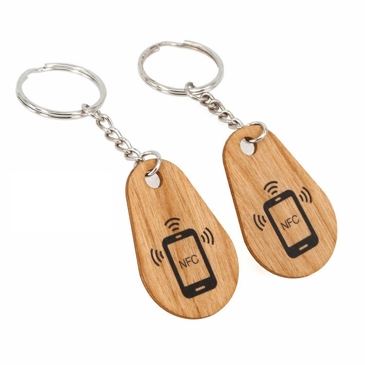 บุคคลหนึ่งใช้พวงกุญแจ RFID ไม้ปลดล็อกเครื่องอ่านประตูอิเล็กทรอนิกส์อัจฉริยะได้อย่างมีประสิทธิภาพในสภาพแวดล้อมสำนักงานทันสมัย