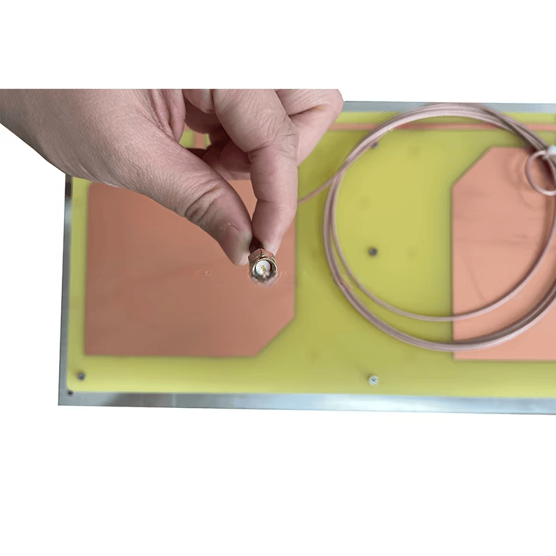 ภาพนี้แสดงส่วนขั้วต่อของเสาอากาศ RFID UHF ลำคลื่นแคบ ZK-ANT9021 ที่ถูกจับด้วยมือเพื่อการตรวจสอบระยะใกล้