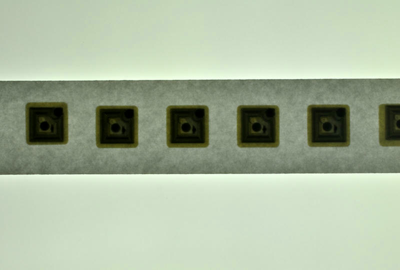 ภาพระยะใกล้แสดงพื้นผิวสีขาวเรียบของฉลาก HF RFID แบบวงกลมบนกระดาษรองที่พร้อมใช้งานสำหรับการควบคุมสต็อกค้าปลีก